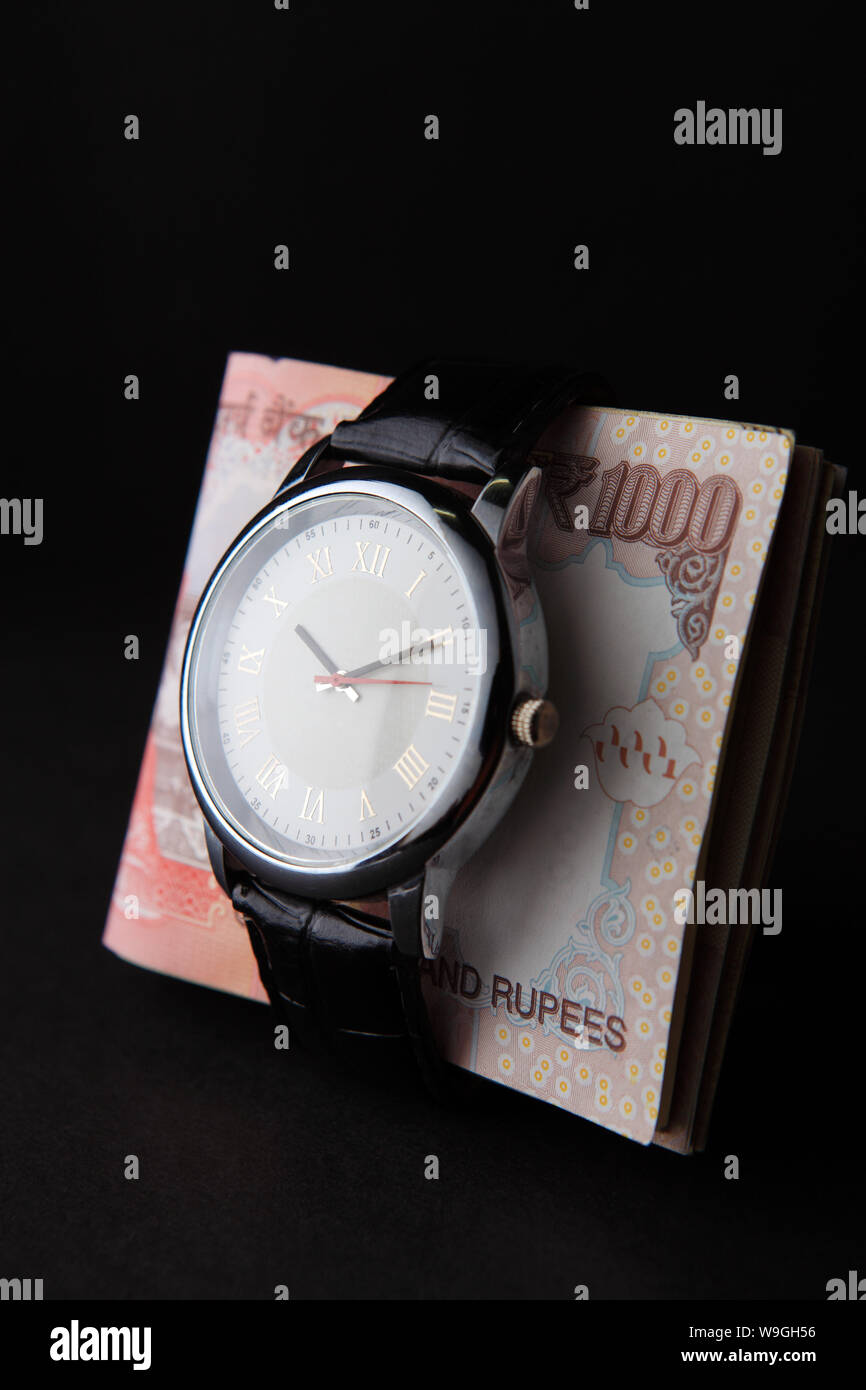 Wristwatch tied up on a bundle of Indian paper currency Stock Photo