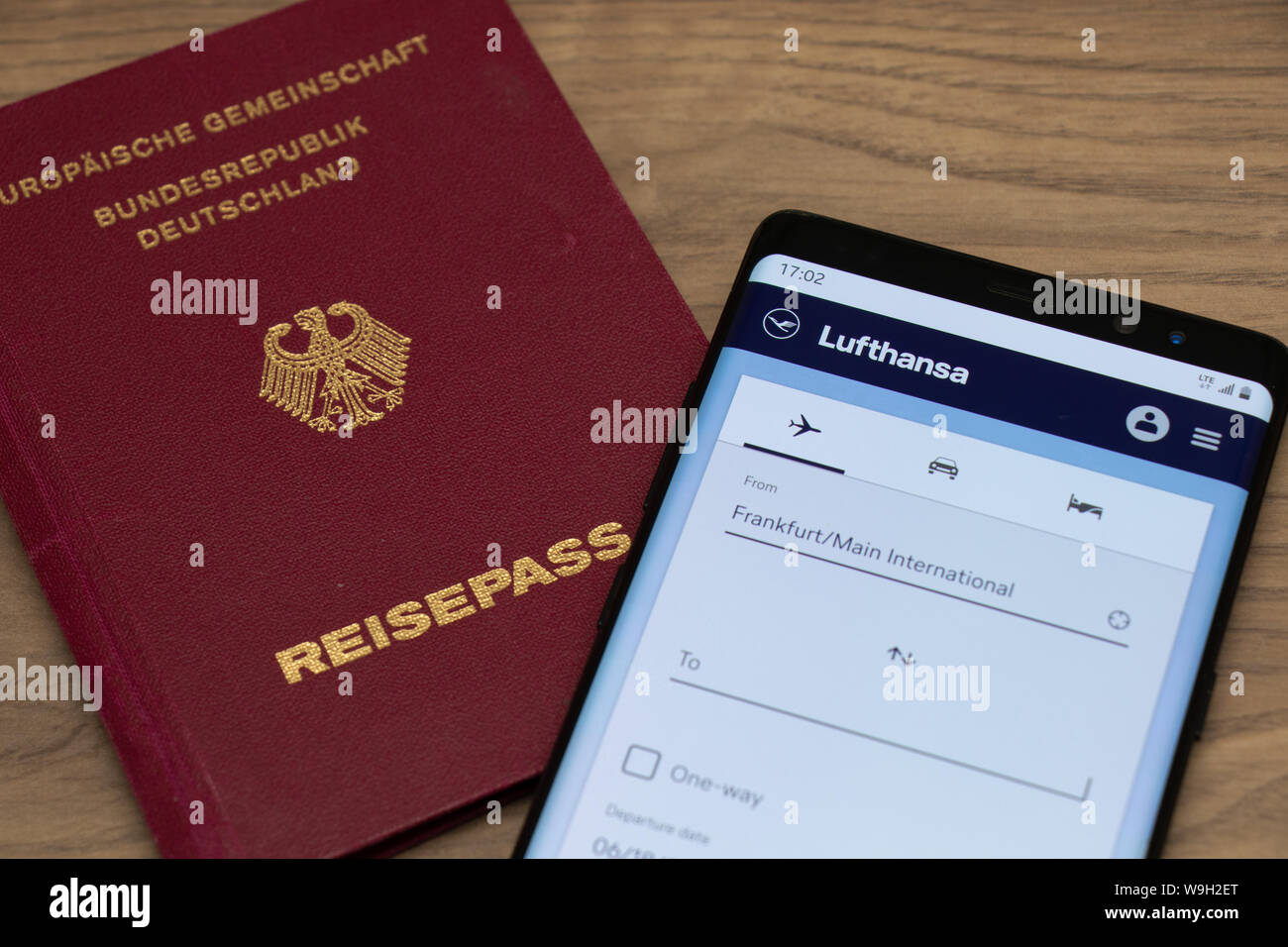 German Passport and Lufthansa website on a smartphone seen while placed on a wooden table. Stock Photo