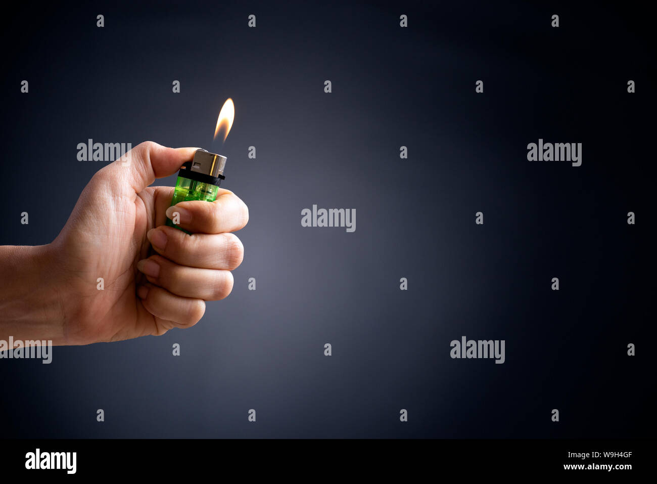 Close up woman hand holding a burning lighter in the dark background