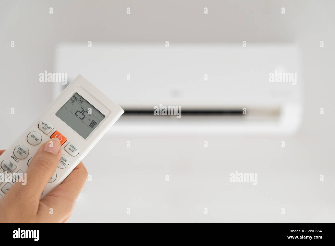 woman hand holding remote controller directed on the air conditioner