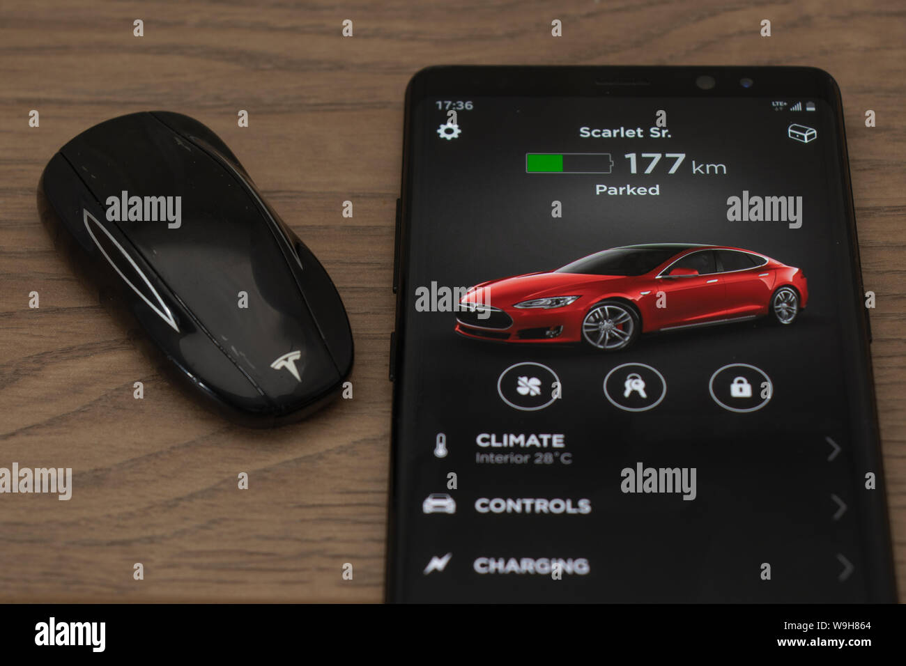 Tesla Model S key fob and Tesla car control app home screen on a smartphone. Stock Photo