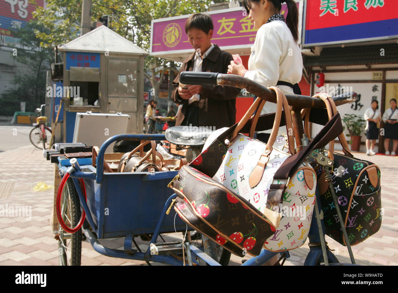 A Chinese vendor sells counterfeit Louis Vuitton bags on the street in Shanghai October 24, 2005. Stock Photo