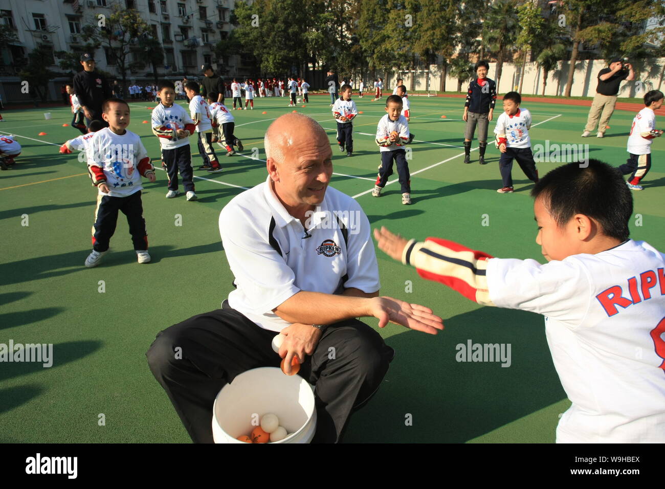 U.S. baseball legend Cal Ripken Jr. (left) teaches a student play baseball during a visit to Da Hu Shan Elementary School in Shanghai, November 2, 200 Stock Photo
