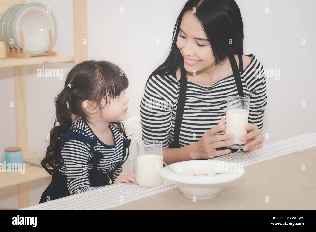 Happy family of asian mom is drinking milk with her cute daughter in the morning. Photo series of family, kids and happy people concept. Stock Photo