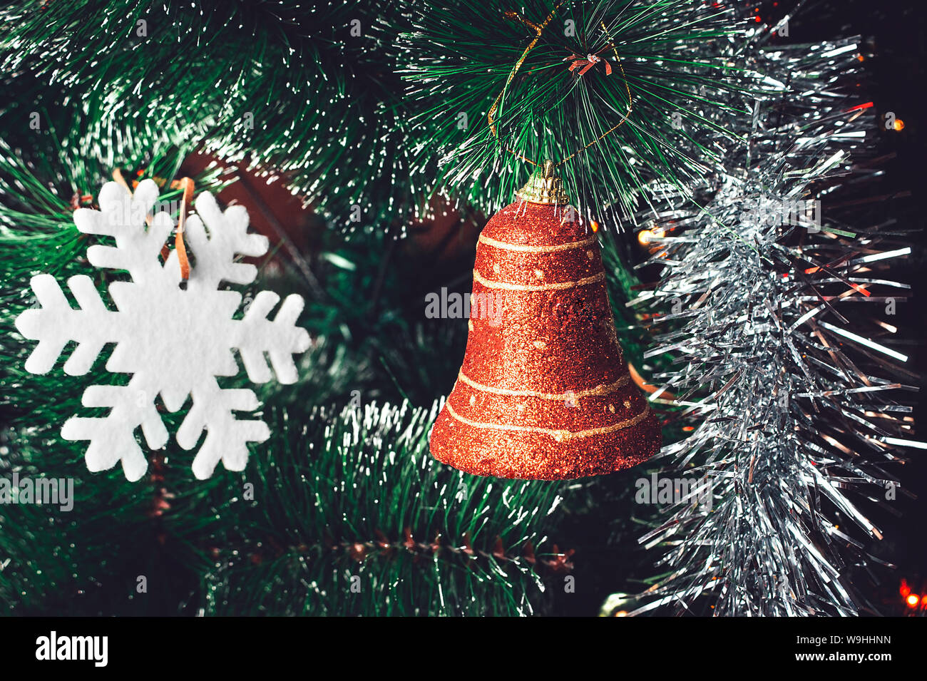 Christmas Tree Decorations: Red Orange Bell, White Snowflake, Shining Silver Tinsel on Green Needles with White Tips. Happy New Year and Christmas Con Stock Photo