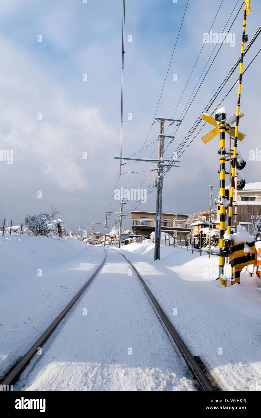 Railway track for local train with white snow fall in winter season,Japan Stock Photo