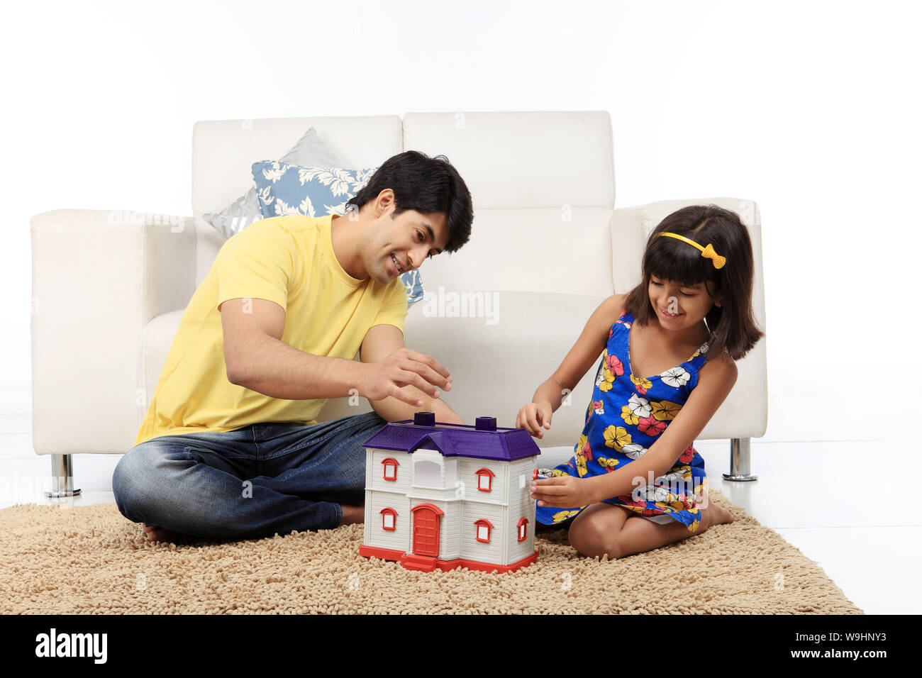 Father and daughter sitting on floor with dream home Stock Photo