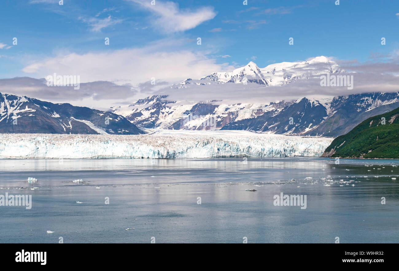 a section of the face of the hubbard glacier in yakutat bay in alaska with the st elias mountains and beautiful clouds in a blue sky in the background Stock Photo