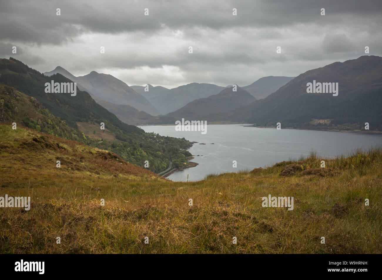 Scottish Loch surrounded by mountainswith a white cottage on the banks of the lake Stock Photo