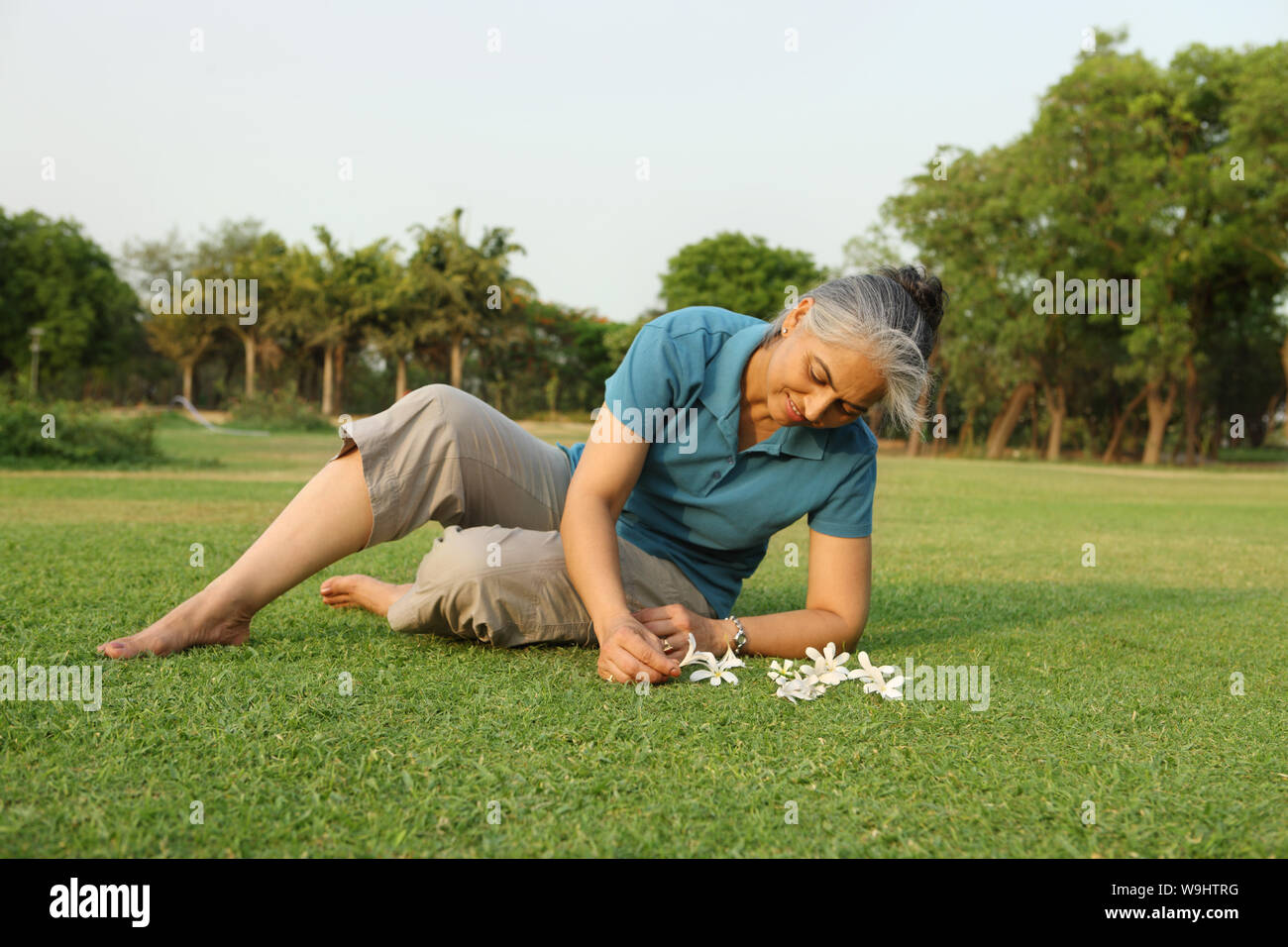 Old woman collecting flowers in a garden Stock Photo