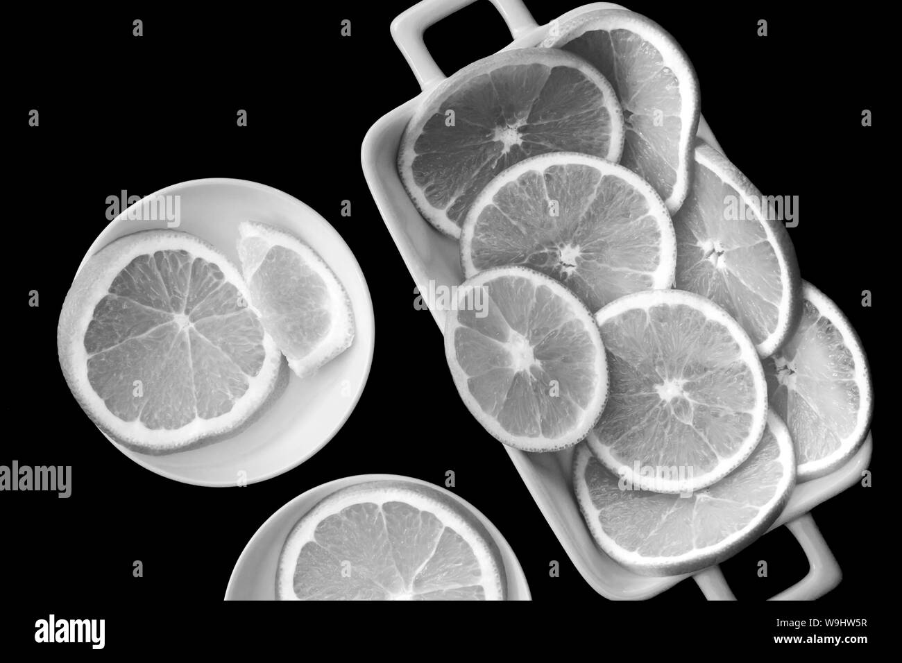 Slices of orange on  plates in black and white. Stock Photo