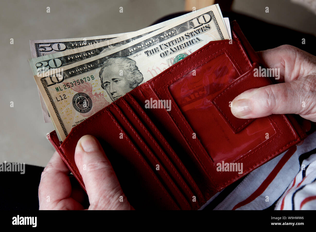 Woman spending American dollars from a red purse. Stock Photo