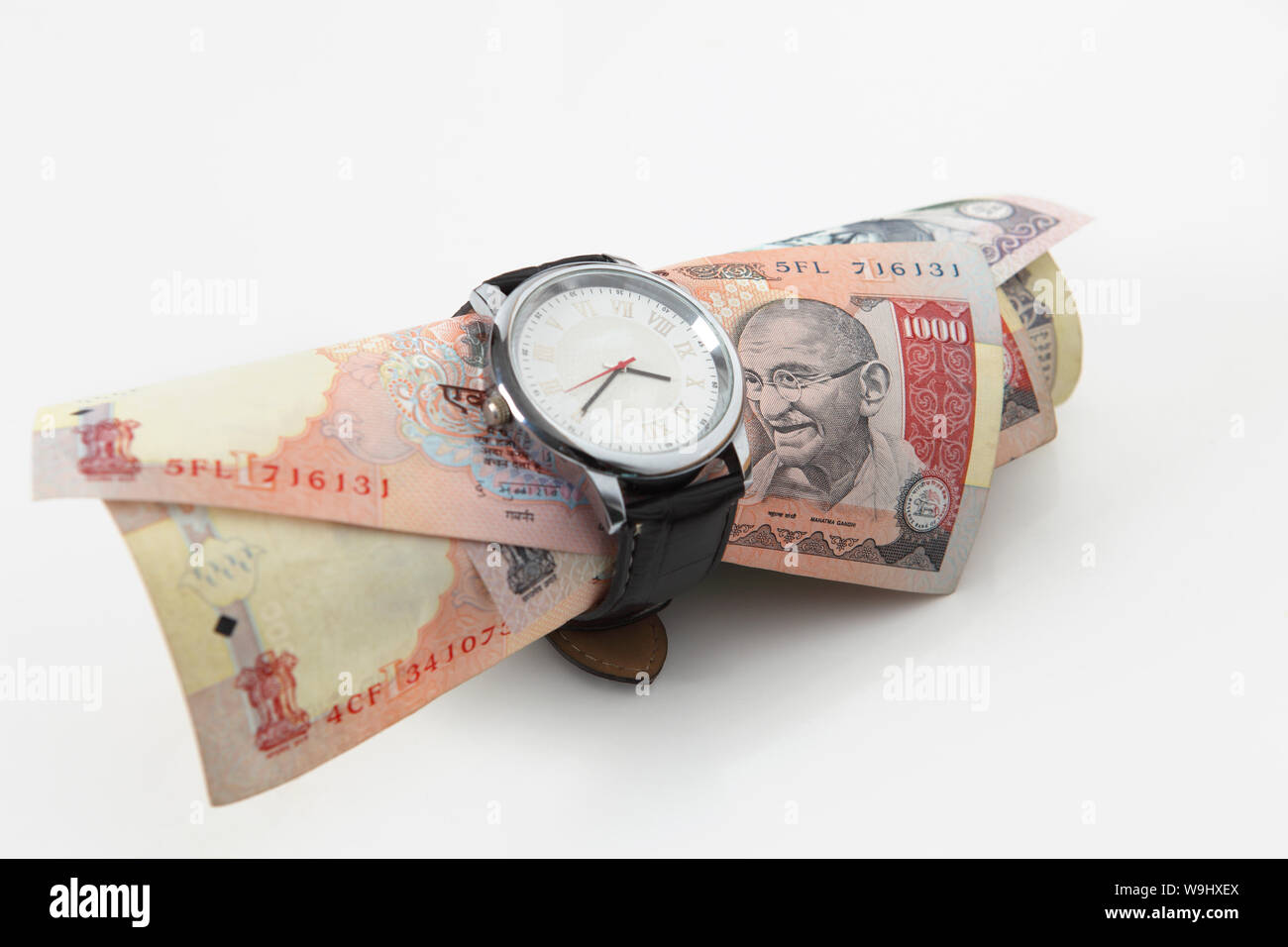 Wristwatch tied up on Indian paper currency Stock Photo