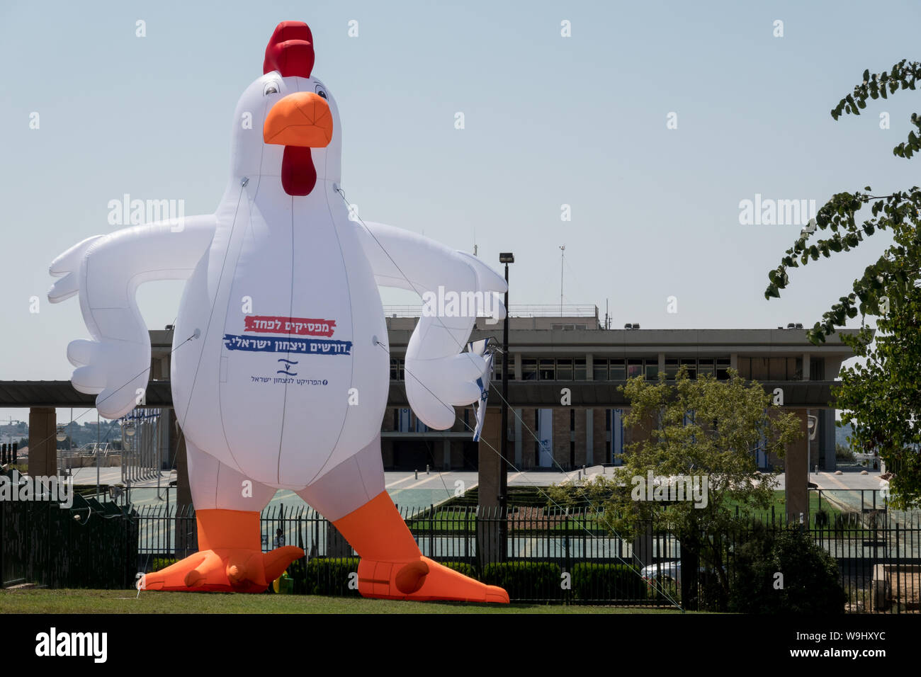 Jerusalem, Israel. 14th August, 2019. The Israel Victory Project sets up a protest installation at the Wohl Rose Garden opposite the Israeli Parliament building opposing government's allegedly submissive policy on Gaza and Palestinian terror. A huge inflatable chicken bears the Hebrew caption “Stop being afraid. We demand an Israeli victory.” Credit: Nir Alon/Alamy Live News. Stock Photo
