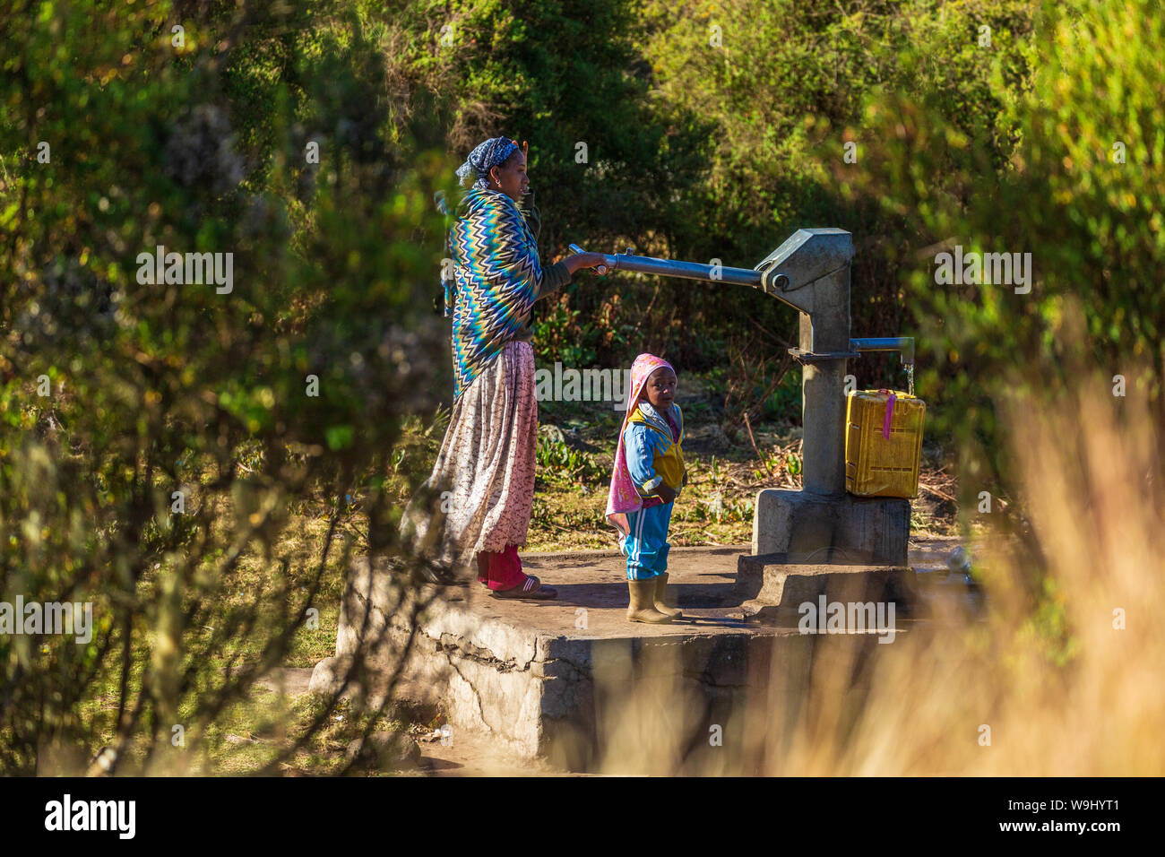 OROMIA, ETHIOPIA-JAN 21, 2019: Unidentified mother with child pumping water from a source. Stock Photo