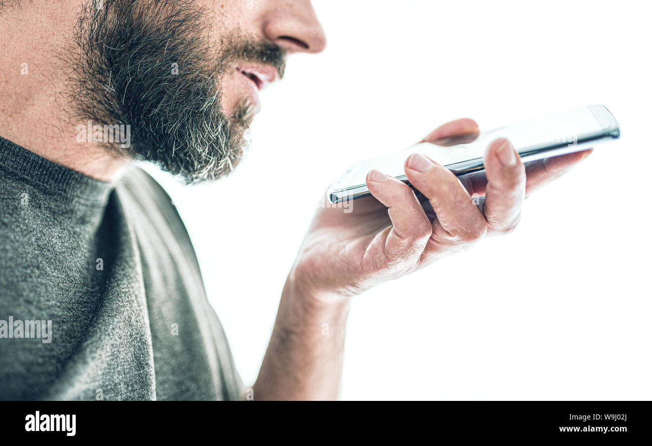 close-up of bearded caucasian man recording voice message or using voice assistant on mobile phone Stock Photo