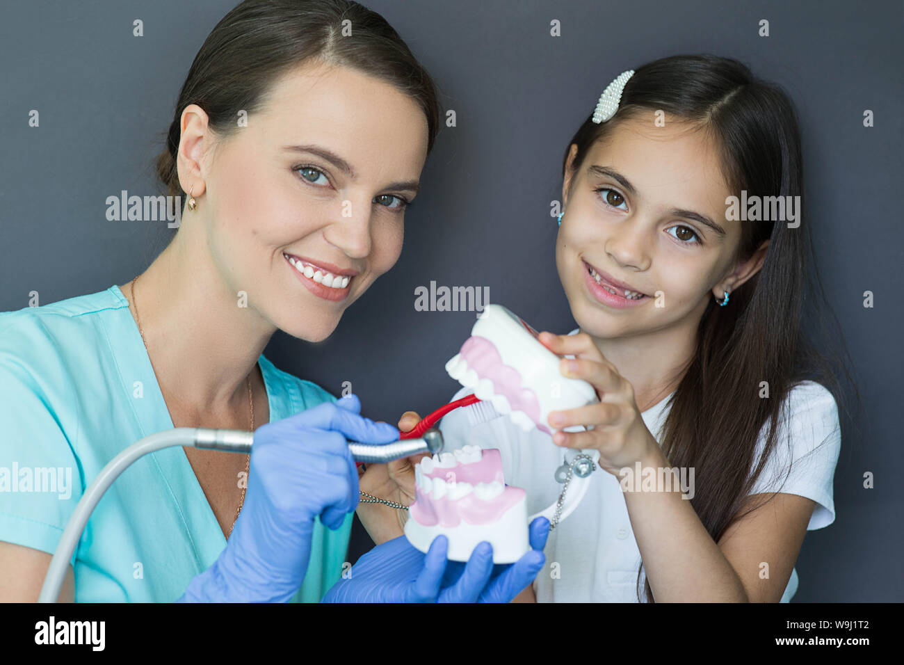 pediatric dentist and mixed race little girl having fun with dental drill and teeth model. Child Teeth treatment Stock Photo
