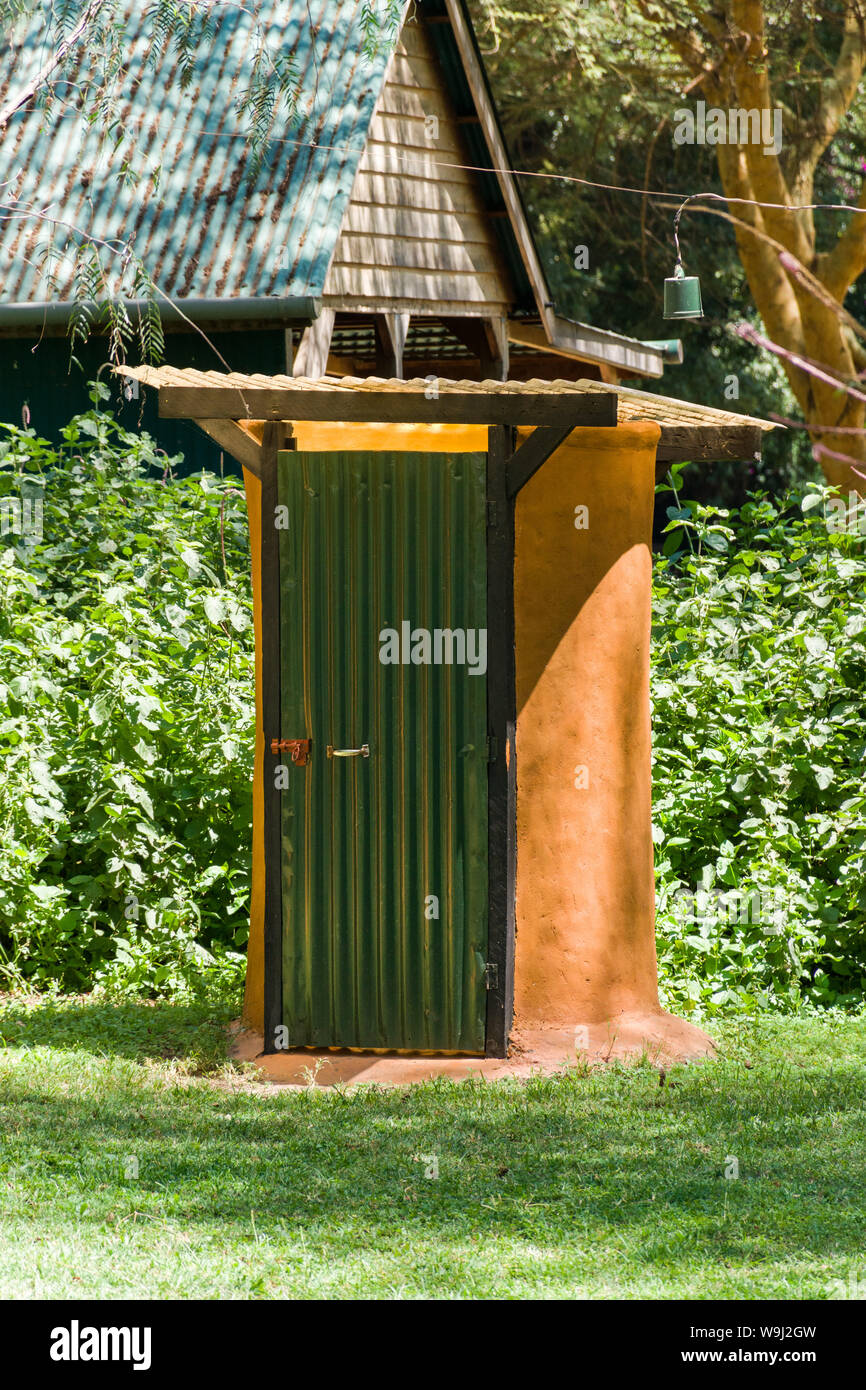 An outdoor camp site drop toilet with corrugated green door, Kenya, East Africa Stock Photo