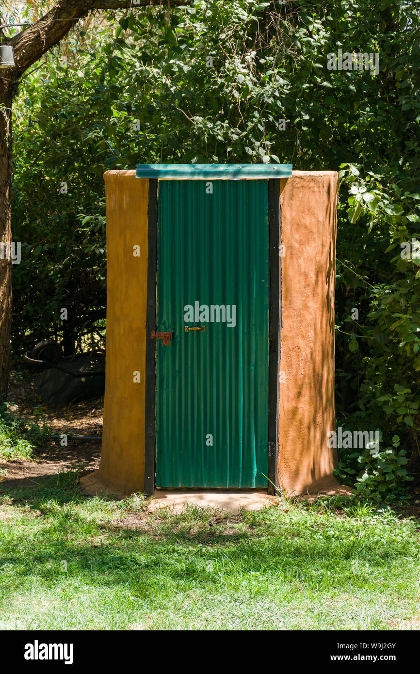 An outdoor camp site drop toilet with corrugated green door, Kenya, East Africa Stock Photo