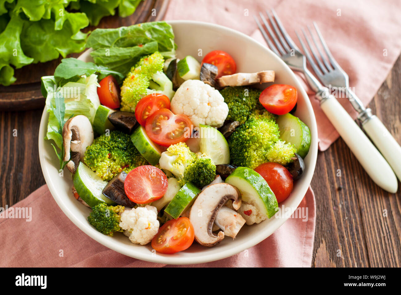 Flavorful Italian salad with marinated vegetables, mushrooms, cherry tomatoes and Parmesan on wooden background Stock Photo