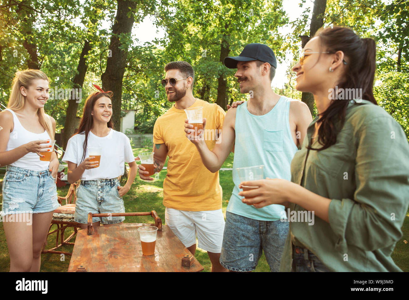 Group of happy friends having beer and barbecue party at sunny day ...