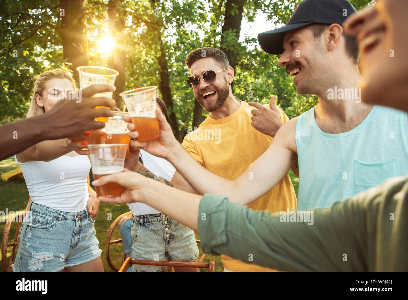 Group of happy friends having beer and barbecue party at sunny day ...