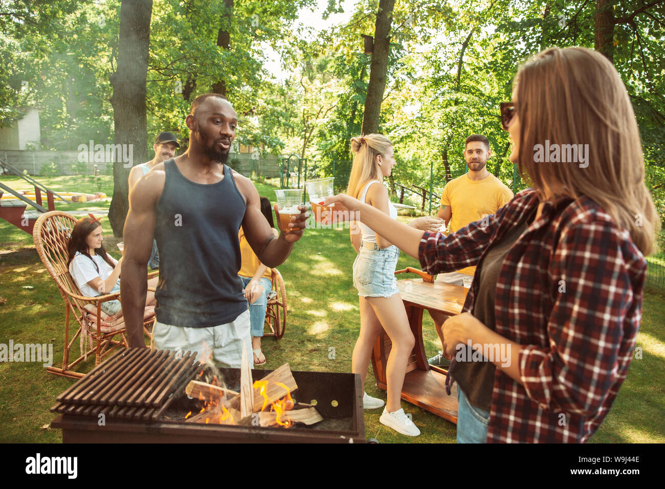 Group of happy friends having beer and barbecue party at sunny day ...