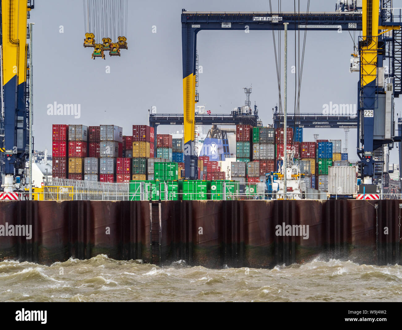 Shipping containers site dockside at Felixstowe port as strong winds delay loading and unloading of containers. Stock Photo