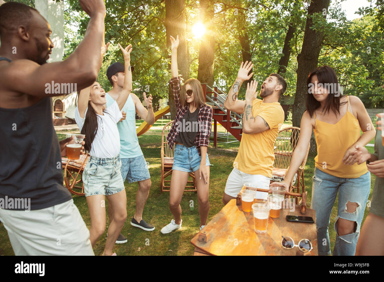 Group of happy friends having beer and barbecue party at sunny day ...
