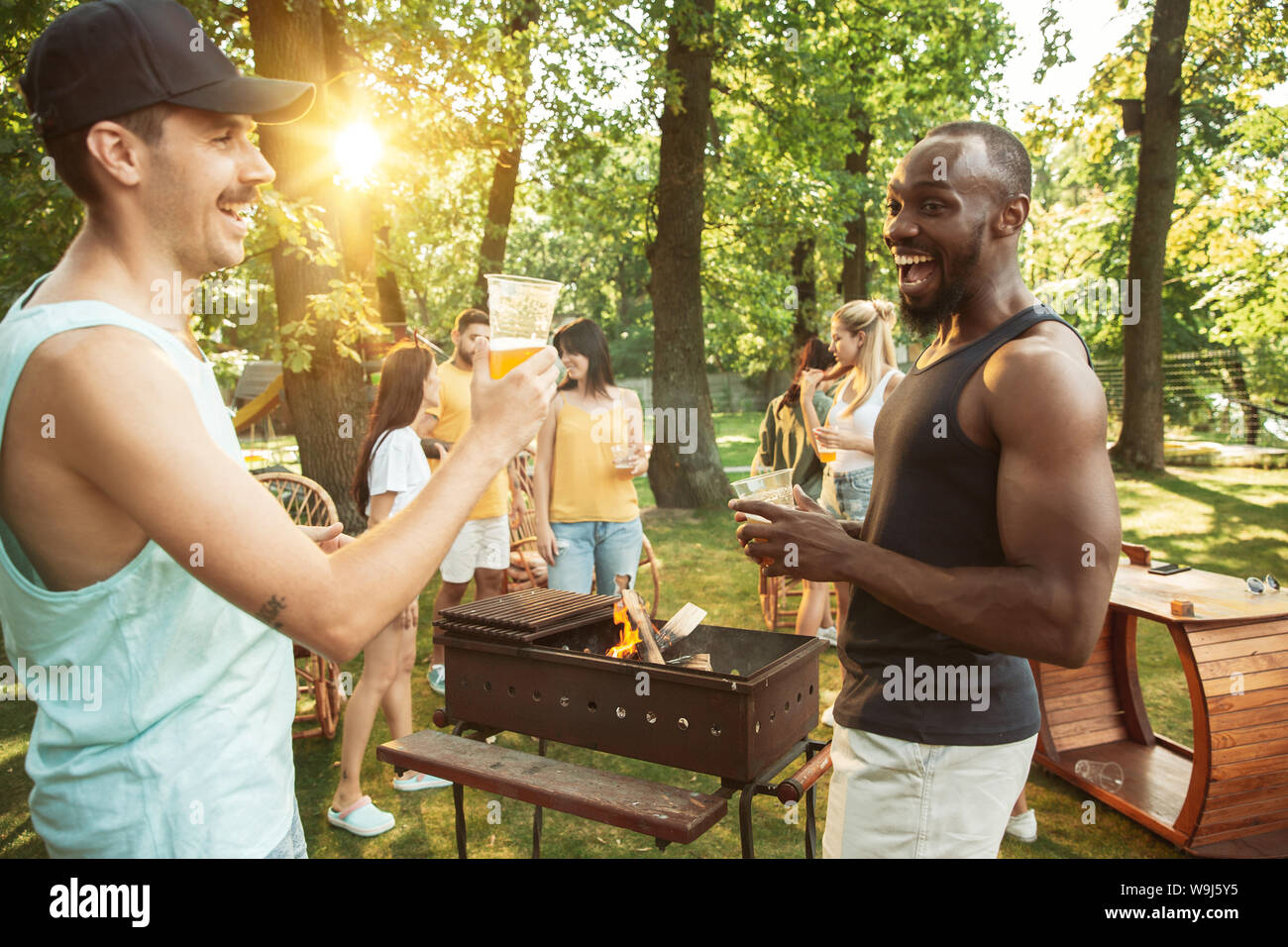 Group of happy friends having beer and barbecue party at sunny day ...