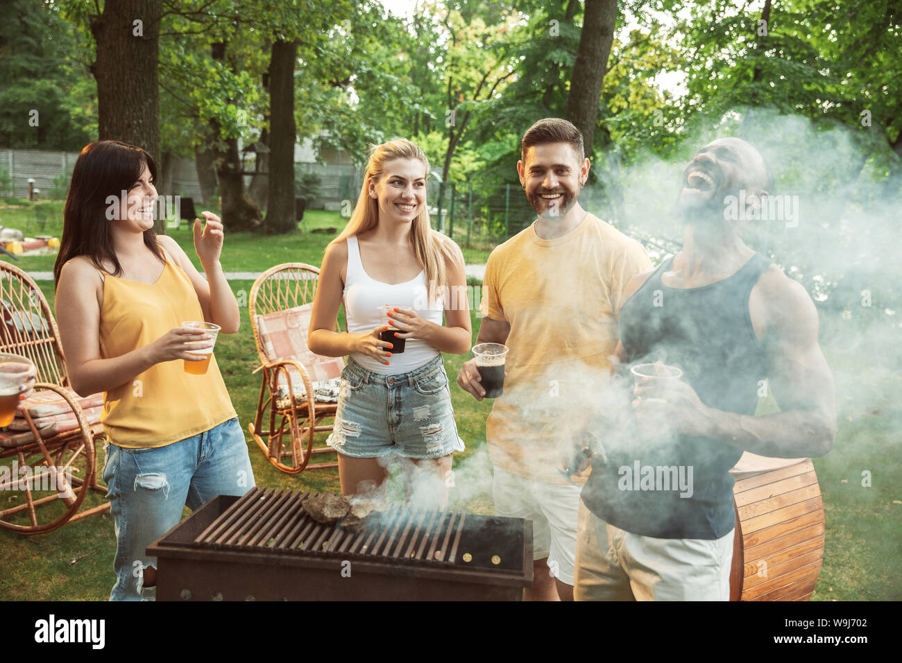 Group of happy friends having beer and barbecue party at sunny day ...