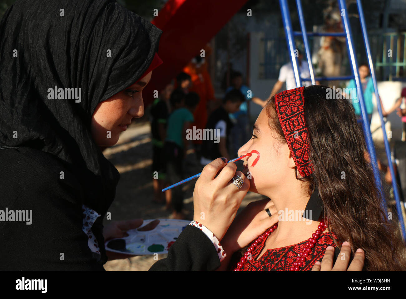 Khan Younis, Gaza Strip, Palestinian Territory. 13th Sep, 2019. A Palestinian volunteer paints on a girl face during an event to celebrate Eid al-Adha festival, in Khan Younis in the southern Gaza Strip, August 13, 2019 Credit: Mariam Dagga/APA Images/ZUMA Wire/Alamy Live News Stock Photo