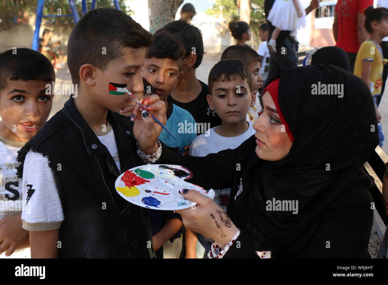 Khan Younis, Gaza Strip, Palestinian Territory. 13th Sep, 2019. A Palestinian volunteer paints on a boy face during an event to celebrate Eid al-Adha festival, in Khan Younis in the southern Gaza Strip, August 13, 2019 Credit: Mariam Dagga/APA Images/ZUMA Wire/Alamy Live News Stock Photo