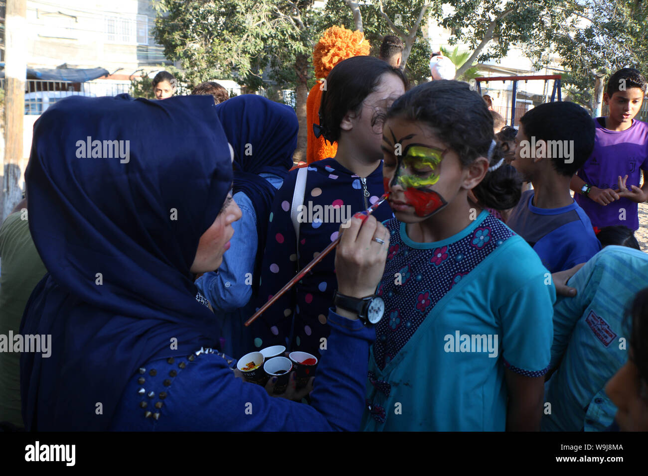 Khan Younis, Gaza Strip, Palestinian Territory. 13th Sep, 2019. A Palestinian volunteer paints on a girl face during an event to celebrate Eid al-Adha festival, in Khan Younis in the southern Gaza Strip, August 13, 2019 Credit: Mariam Dagga/APA Images/ZUMA Wire/Alamy Live News Stock Photo