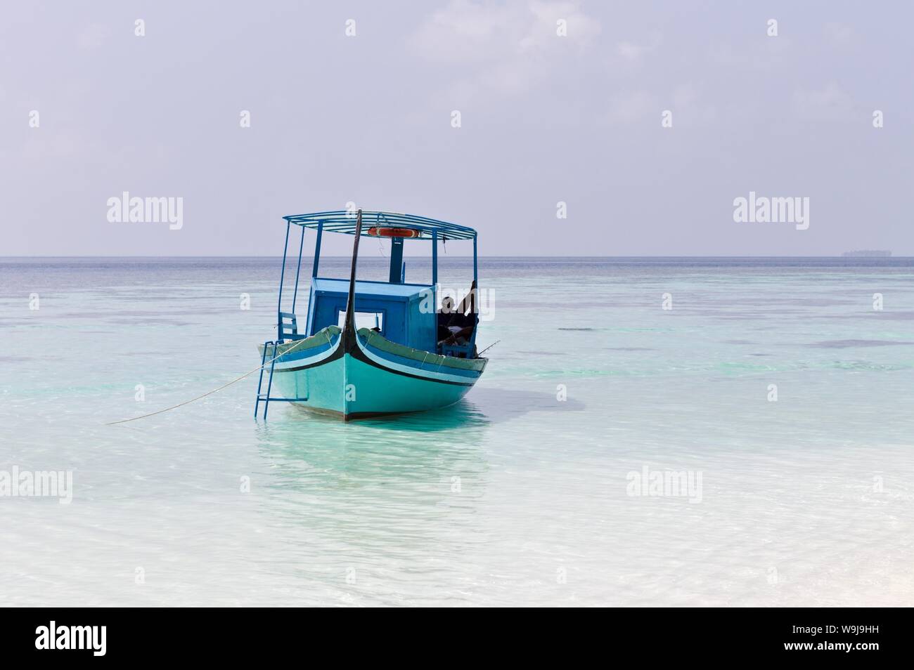 Ari Atoll, Maldives - 25 December 2018: A maldivian sailor is fishing on his blue boat called 'dhoni' Stock Photo