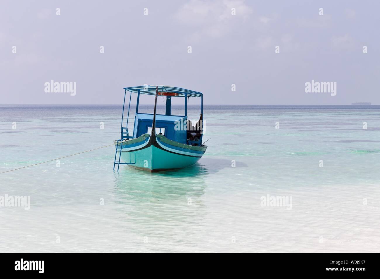 Ari Atoll, Maldives - 25 December 2018: A maldivian sailor is fishing on his blue boat called 'dhoni' Stock Photo