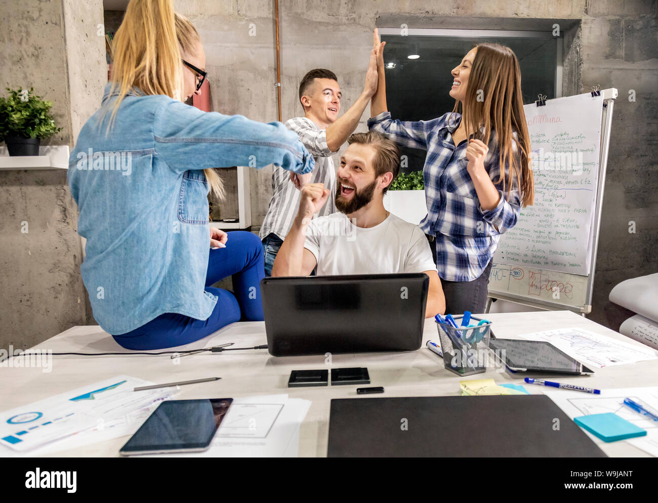 Young office workers congratulate each other on their success in a loft workspace Stock Photo