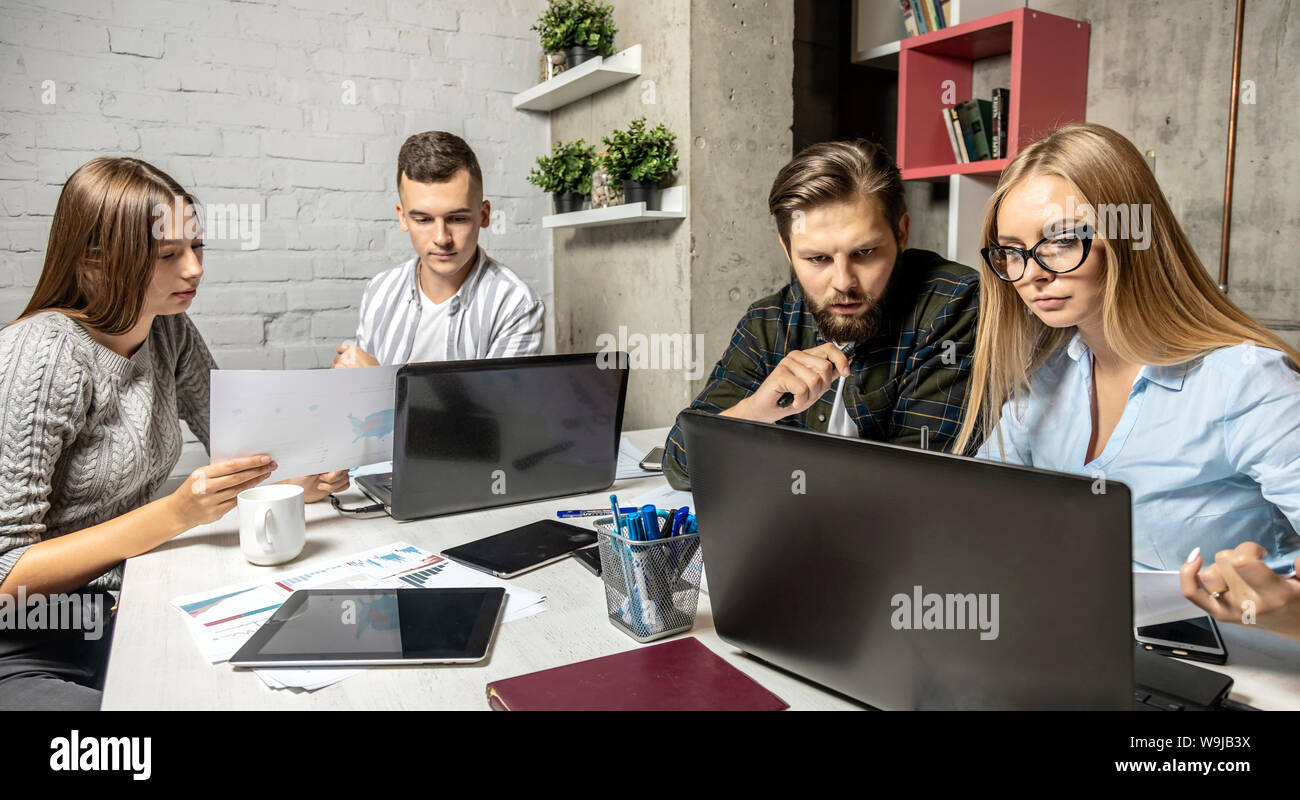 Young creative office cooperative colleagues work in pairs in loft workspace Stock Photo