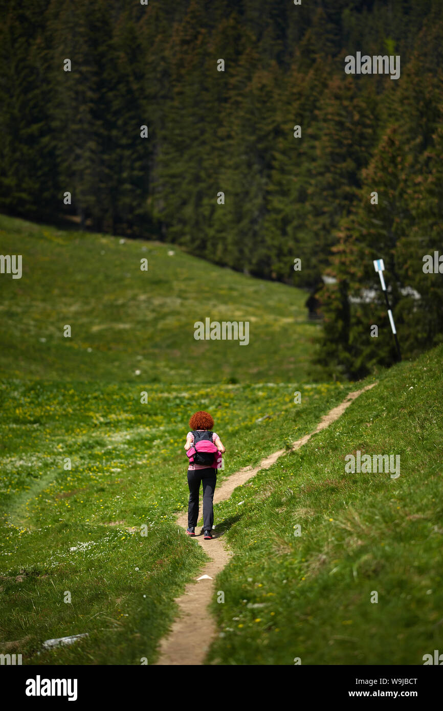 Curly redhead woman hiking on a trail in the mountains Stock Photo - Alamy