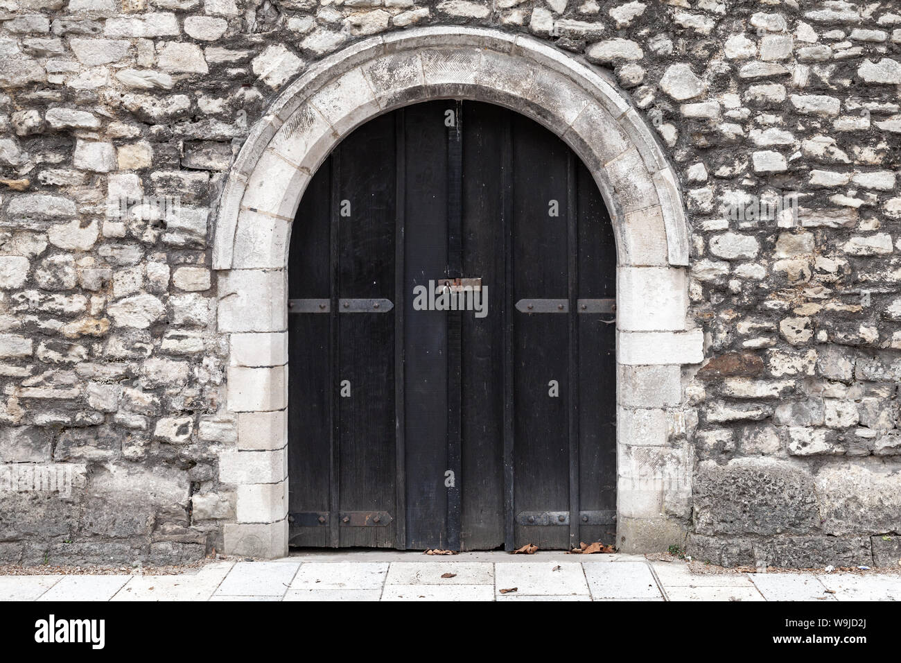 Closed black wooden door in old stone wall, background photo texture ...