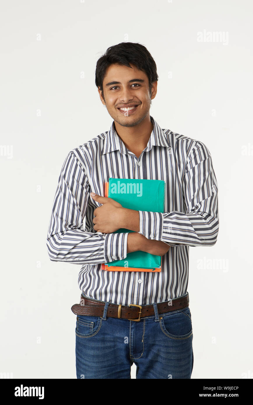 College student holding books and smiling Stock Photo - Alamy