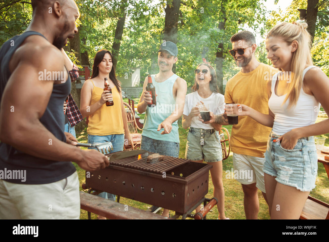 Group of happy friends having beer and barbecue party at sunny day ...