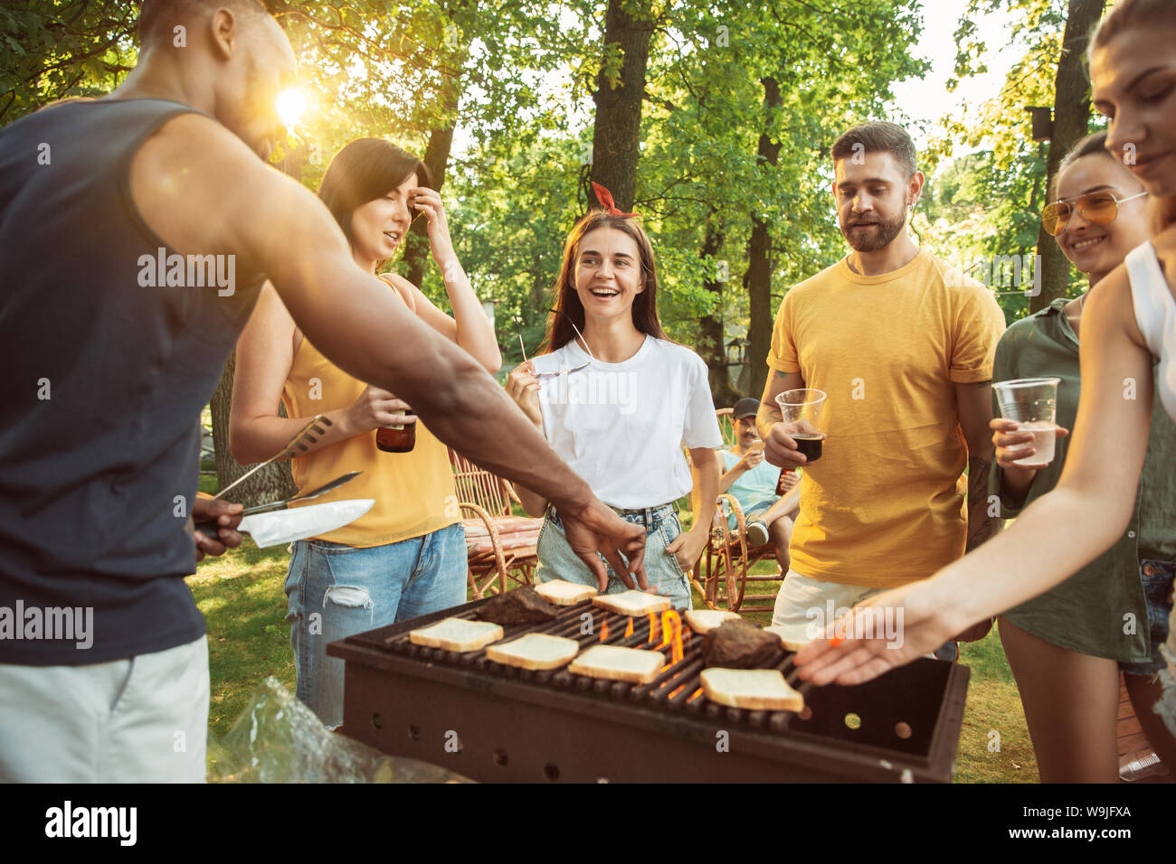 Group of happy friends having beer and barbecue party at sunny day ...