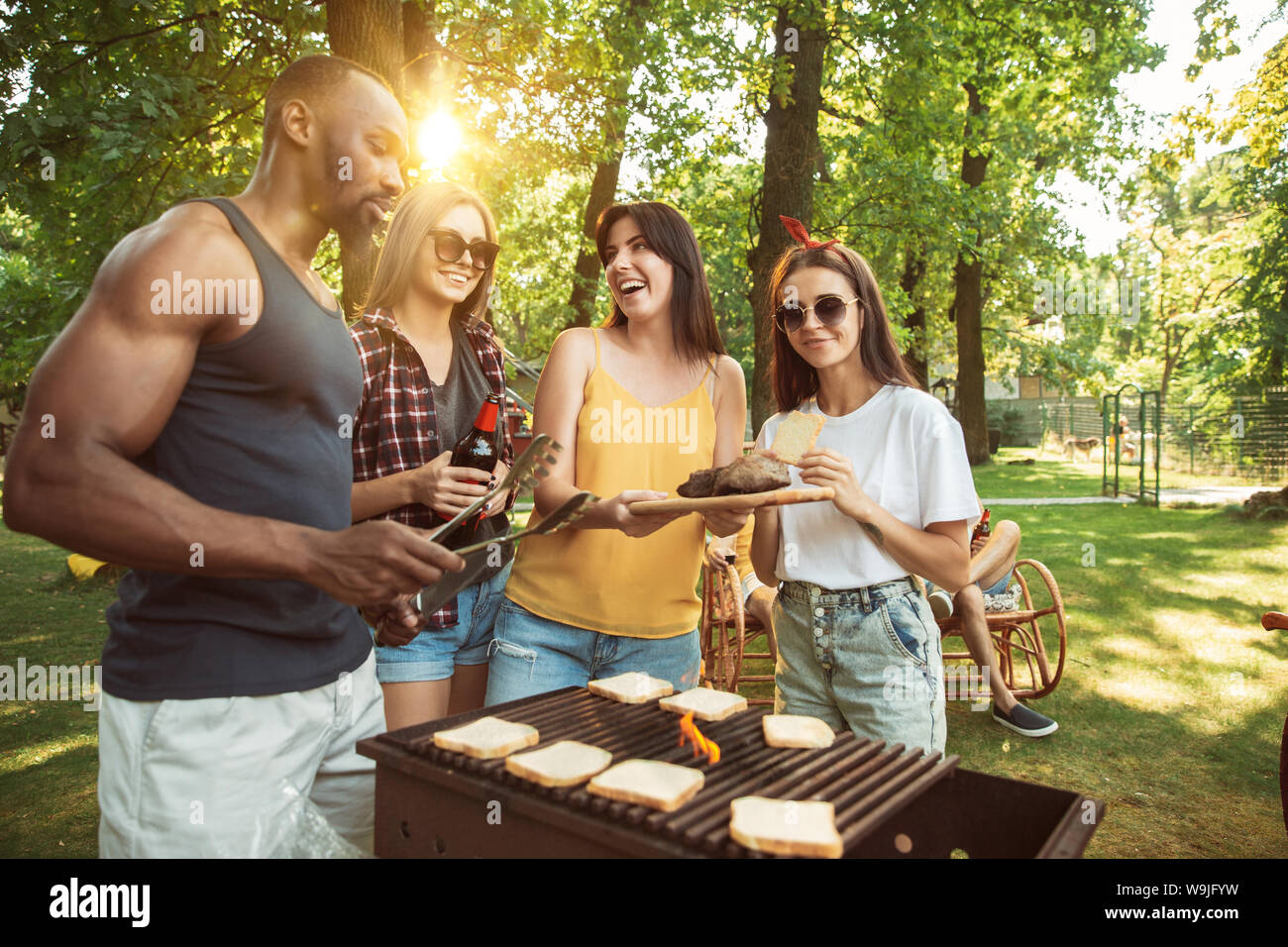 Group of happy friends having beer and barbecue party at sunny day ...