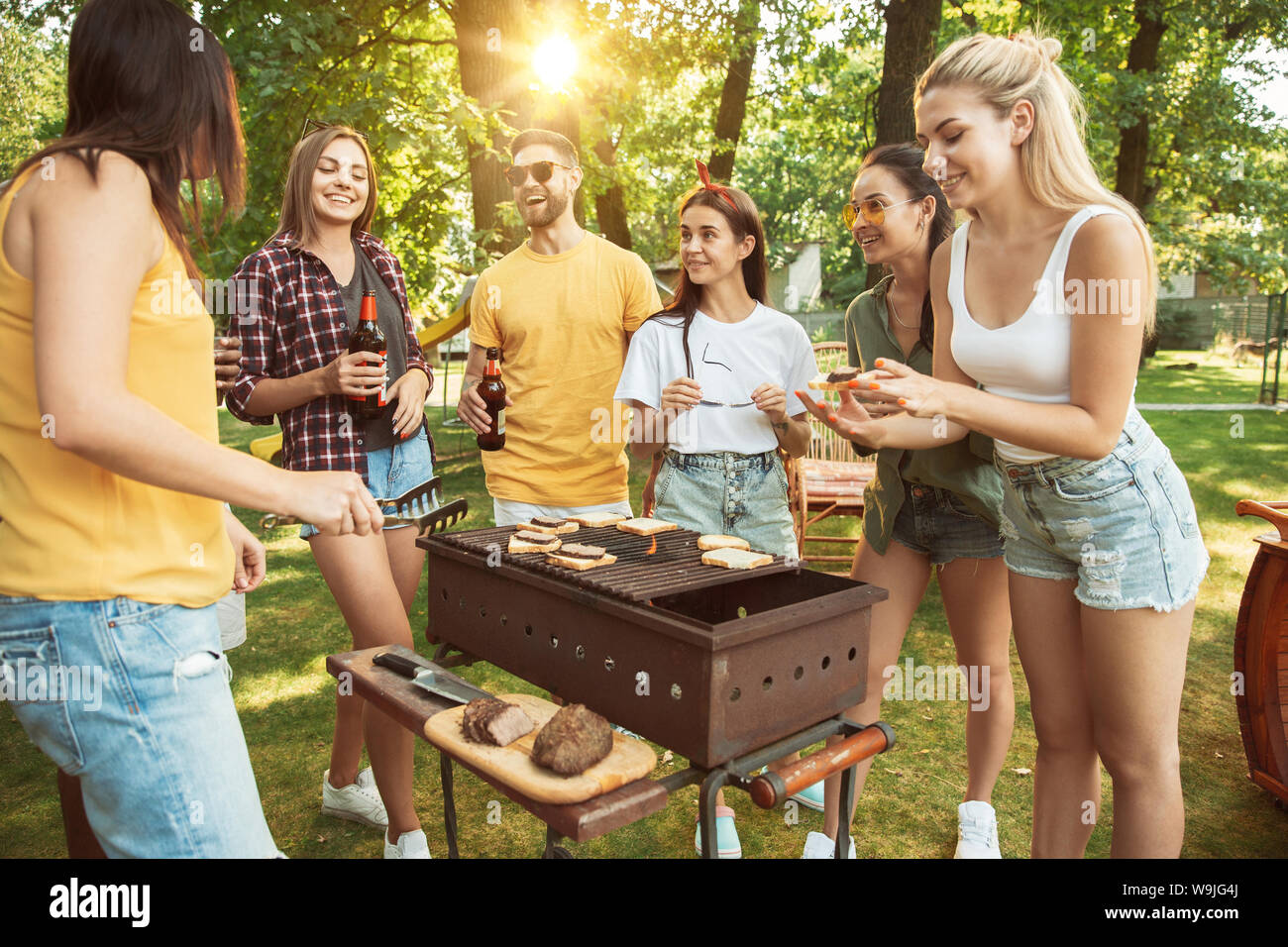Group of happy friends having beer and barbecue party at sunny day ...