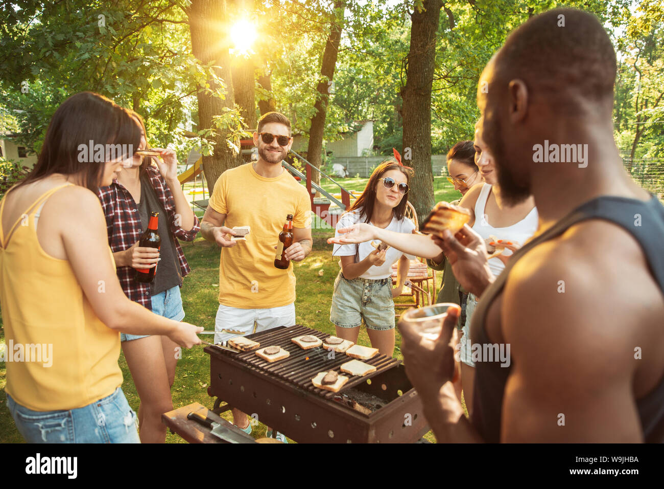 Group of happy friends having beer and barbecue party at sunny day ...