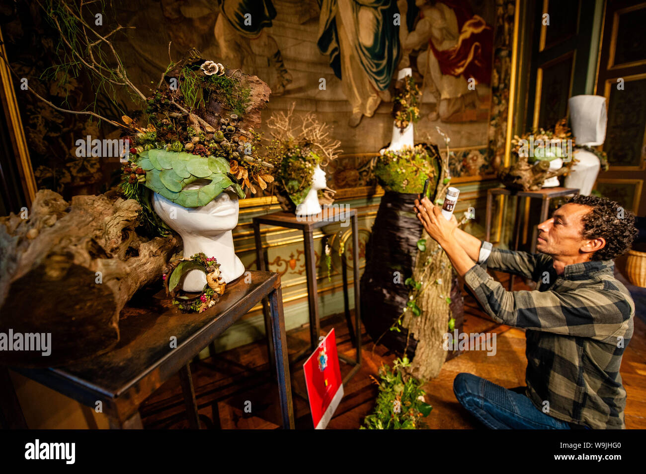 Brussels, North Brabant, Belgium. 14th Aug, 2019. A man takes a photo of one of the floral piece of art during the occasion.Flower time is a biennial initiative that was launched in 2013 by the City of Brussels and the ASBL (non-profit organization) Tapis de Fleurs de Bruxelles. Under the theme 'A World of Floral Emotions', more than 30 top florists from 13 countries decorated the magnificent rooms of Brussels City Hall, a Unesco masterpiece of Gothic architecture. Brussels' famous Grand Place hosted for the occasion a stunning flower arch composed of 500 fuchsias. This year, the artistic Stock Photo