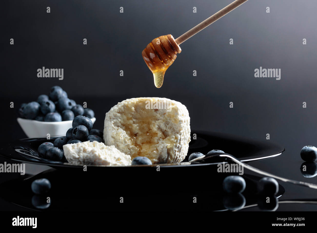 Cottage cheese with honey and blueberry on a black background. Copy