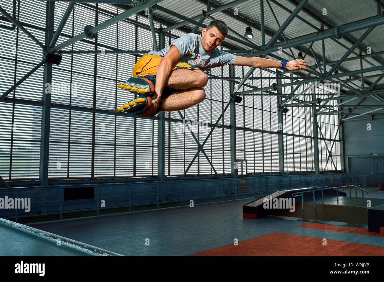 Rollerblader jump high from big air ramp performing trick. Indoors