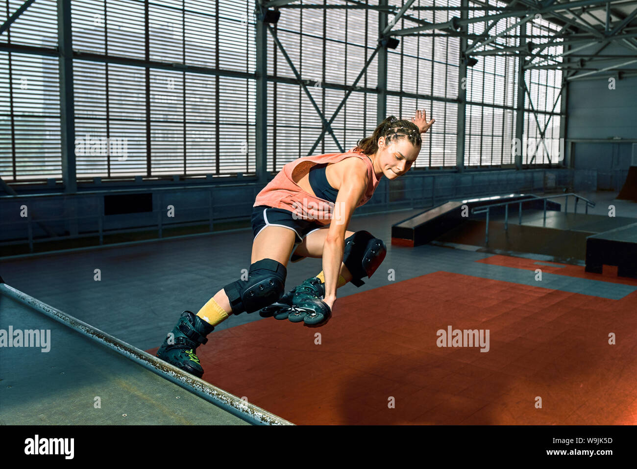 Rollerblader jump high from big air ramp performing trick. Indoors